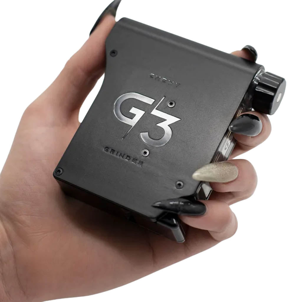 Person holding the Chewy G3 Deluxe Electronic Grinder, displaying the G3 logo on its sleek black casing.