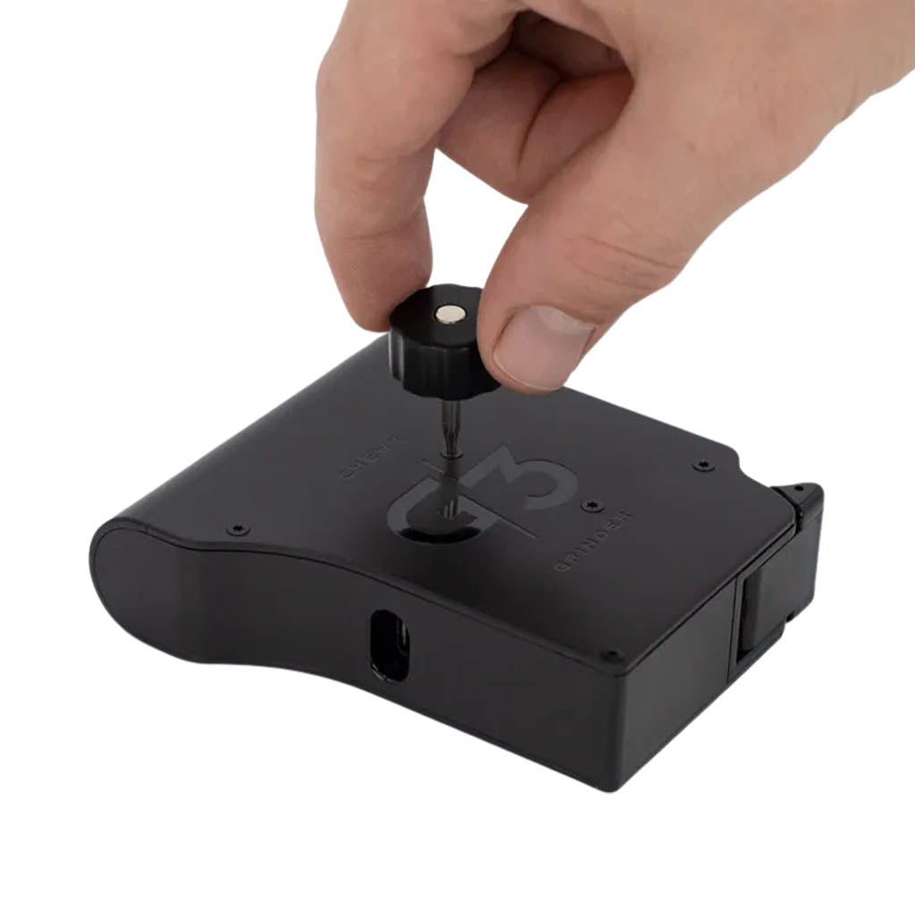 Hand unscrewing the top screw cap of the Chewy G3 Deluxe Electronic Grinder for loading herbs.