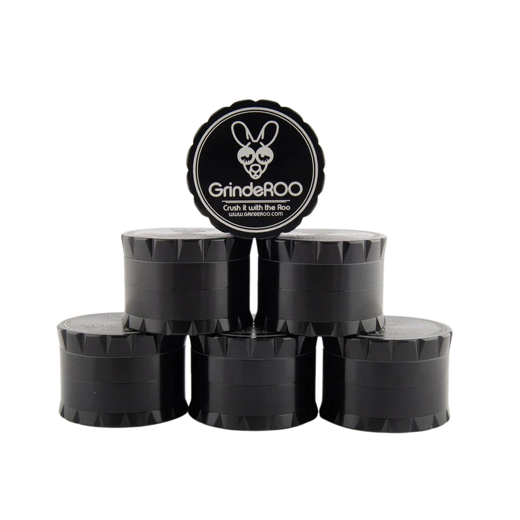 Stacked display of six black GrindeROO OG 4-part metal herb grinders with one unit standing upright to showcase the branded lid design.