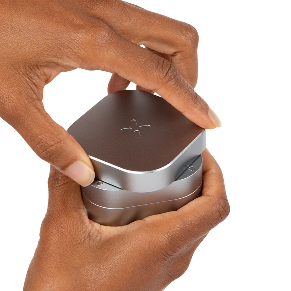 Hands twisting open the 3 Piece Heavy-Duty Aluminum Grinder in silver, showcasing its ergonomic and durable design.